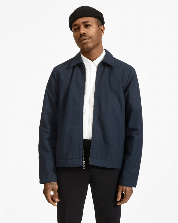 male model wearing a navy colored canvas jacket from Everlane