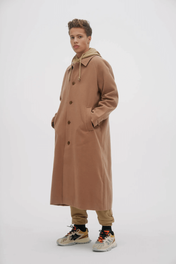 male model wearing a long, tan colored vegan wool coat from NOIZE