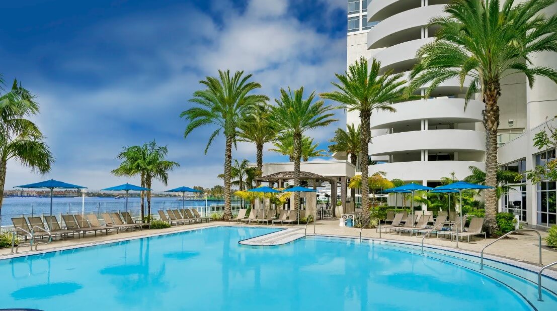 An outdoor swimming pool surrounded by chairs and palm trees