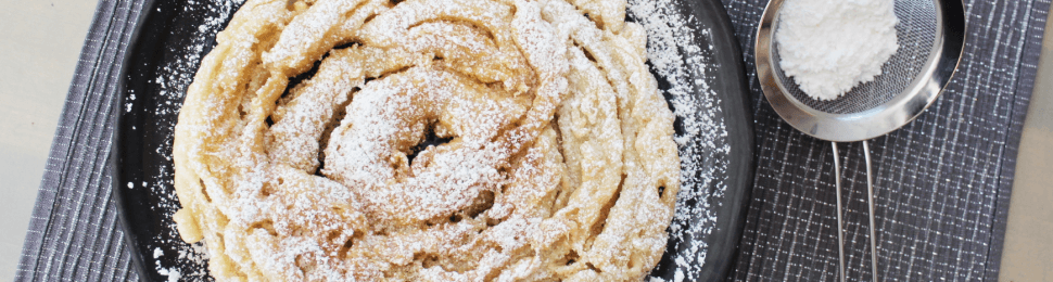 a vegan funnel cake topped with powdered sugar on a blue placemat