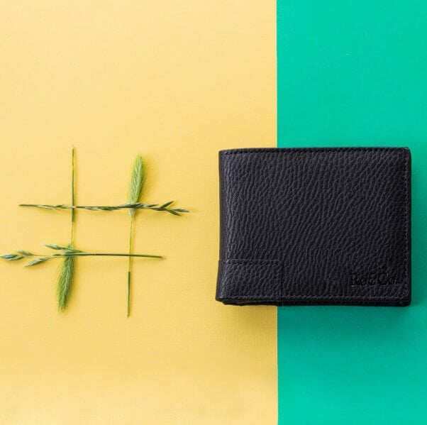 photo of black vegan wallet against a peach and blue backdrop