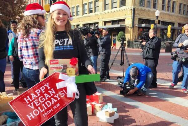 PETA supporter in Santa hat in front of press representatives