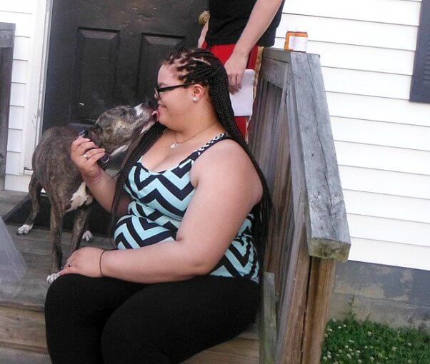 Dog kissing woman sitting on staircase