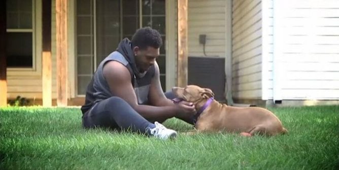 Ronnie Stanley hugging dog on grass