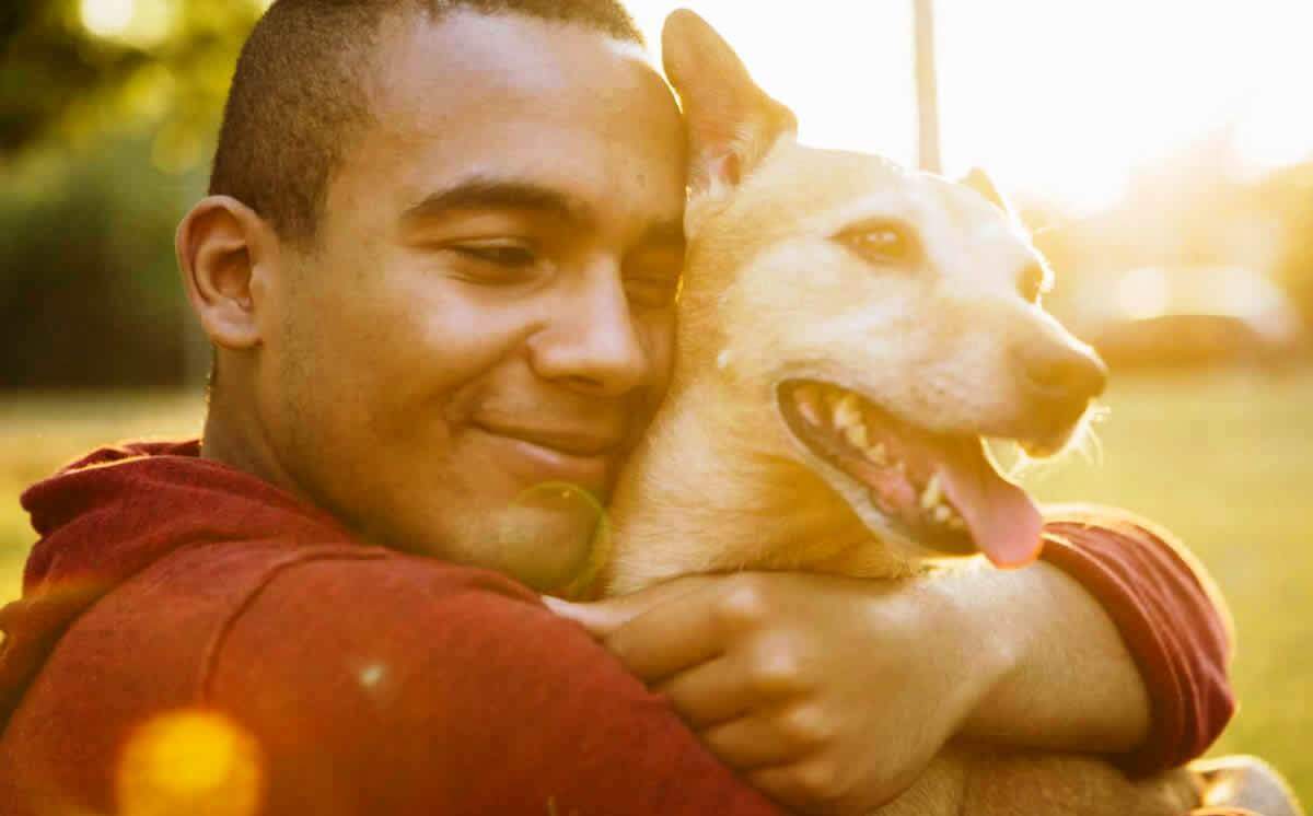 Man hugging small brown mixed-breed dog