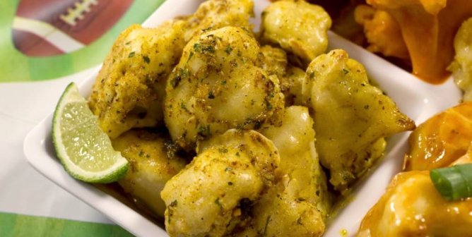 Baked vegan cauliflower wings with curry and lime garnish