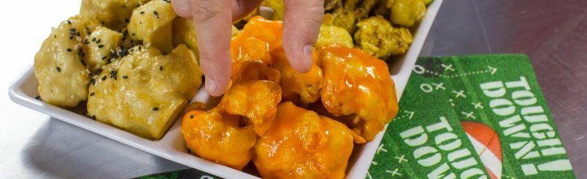 Hand picking up a buffalo vegan cauliflower wings