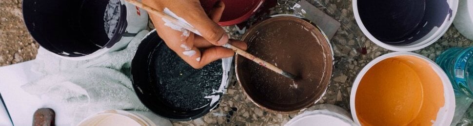 Painter reaching over multiple paint cans to choose a color of paint.