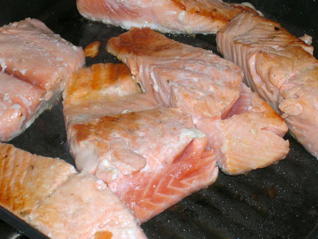 Salmon flesh baking on sheet with oozing white goo