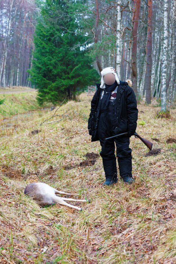 Hunter with blurred face next to dead dear