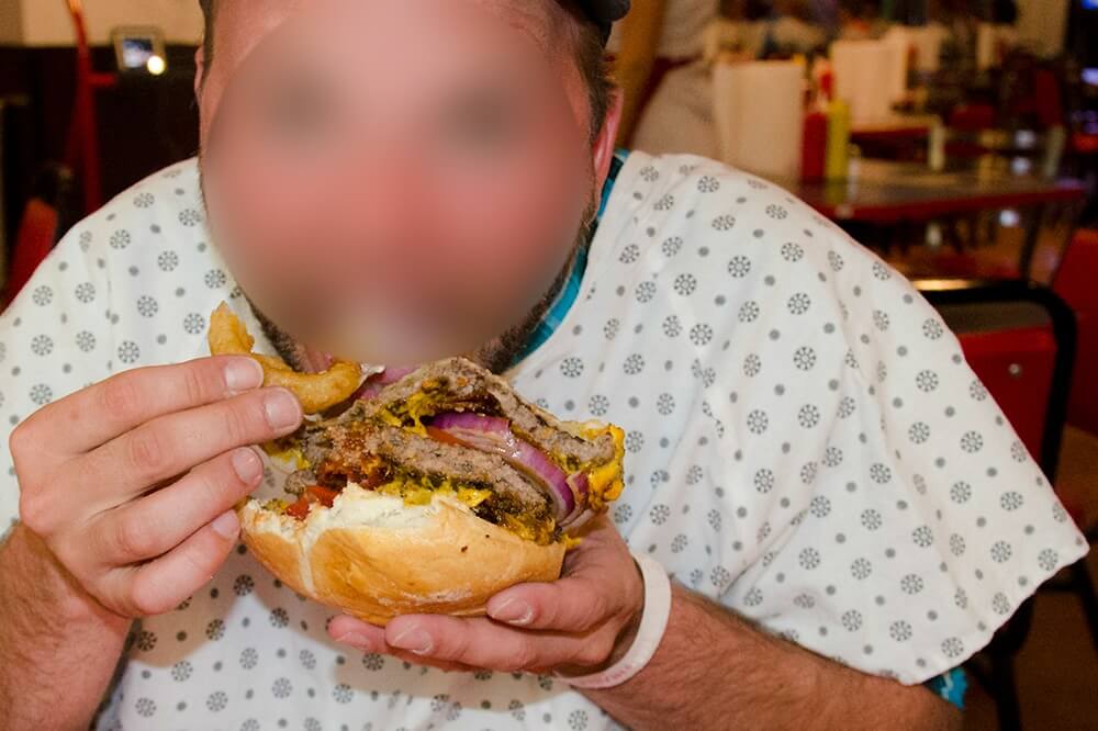 Man in hospital gown eating burger