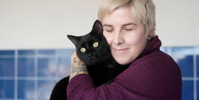 Pretty black cat being snuggled by PETA fieldworker