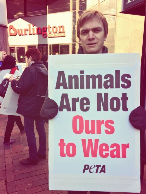 A PETA staffer holds a sign reading "Animals Are Not Ours to Wear" outside Burlington Coat Factory