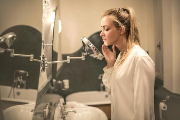 woman looking at her skin in a mirror