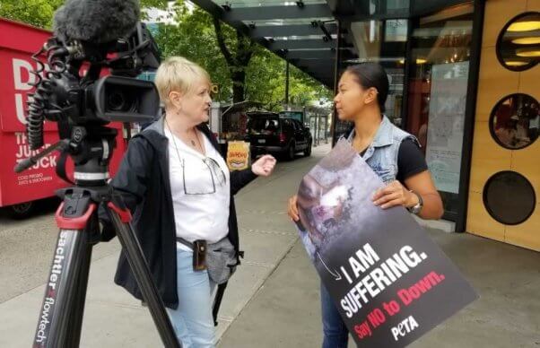 PETA supporter holding anti-down side talks with press outside lululemon shareholder meeting