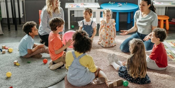 Teacher and kids on the floor in a happy classroom.