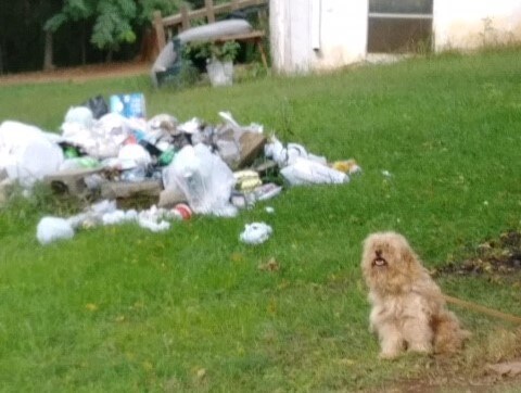 Theodore in front of a pile of garbage at his former home