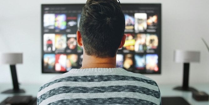 a man looking at a tv screen full of movie streaming options