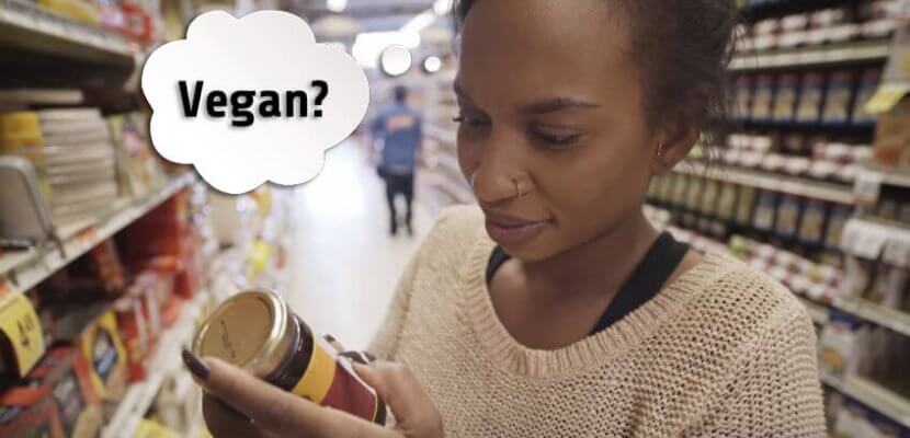 person shopping and looking at a label for the word 'vegan'