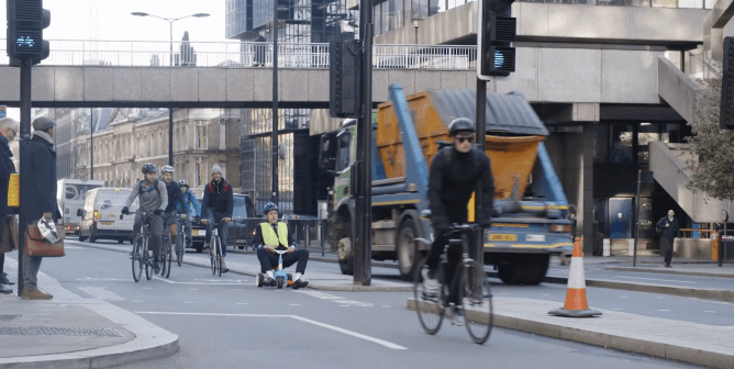 grown man rides tricycle on a busy street