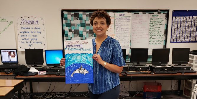 teacher holding student artwork