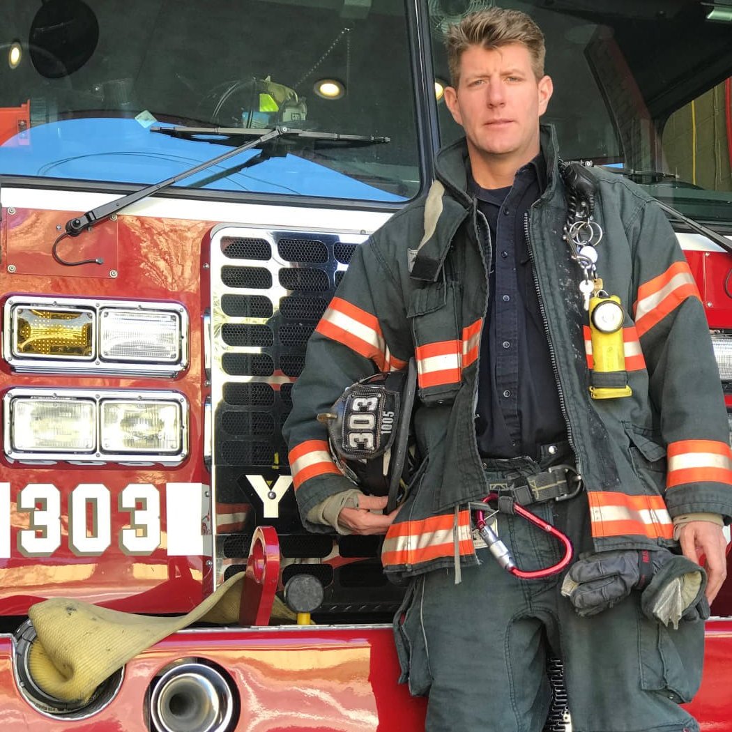 a man in a firefighters uniform stands in front of a fire truck