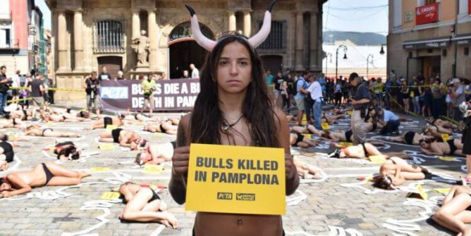 woman holds sign saying "bulls killed in pamplona"