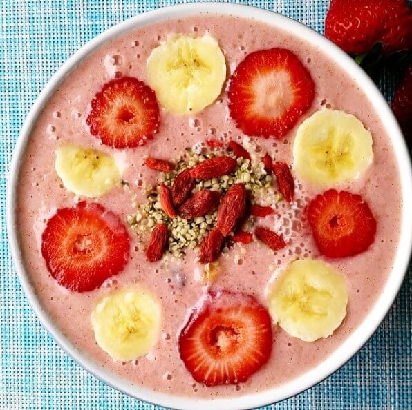 strawberry smoothie bowl topped with sliced banana and strawberries