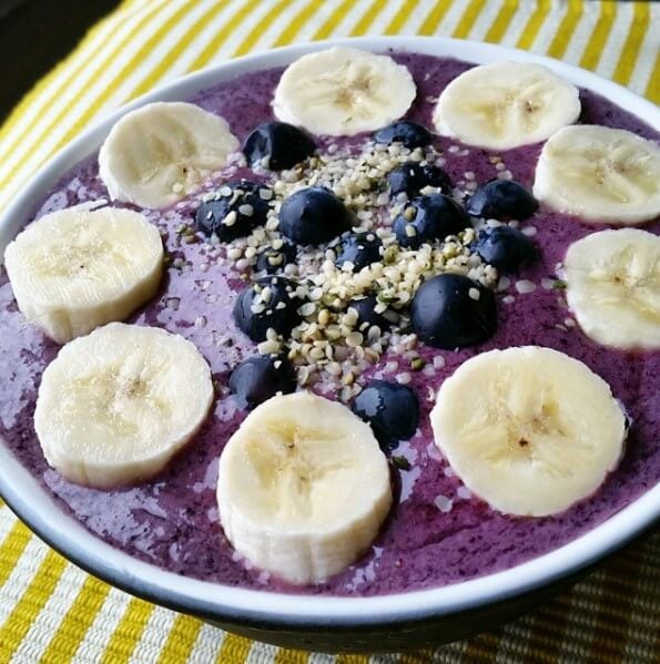 blueberry smoothie bowl topped with bananas and blueberries