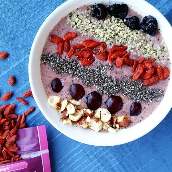 acai smoothie bowl topped with berries, seeds, and nuts