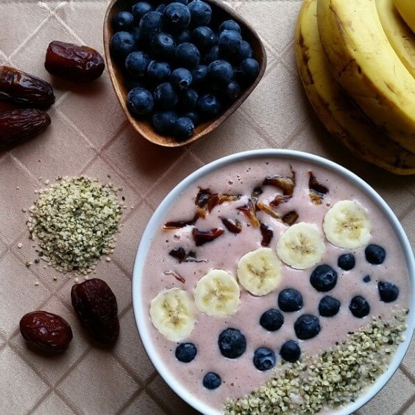 strawberry smoothie bowl topped with blueberries, banana, seeds, dates