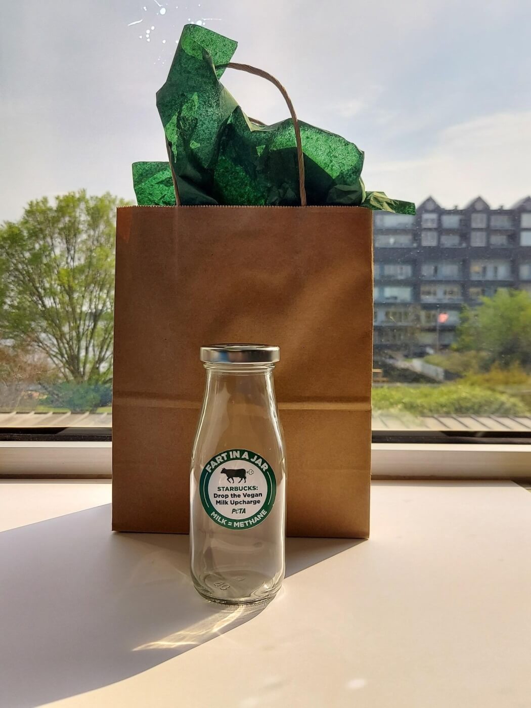 gift bag behind a mock Starbucks bottle containing a cow fart that PETA sent to the coffee giant's CEO for Earth Day