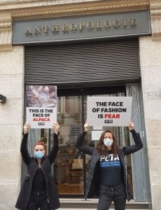 PETA affiliates standing outside Anthropologie, owned by Urban Outfitters Inc., holding signs that say "the face of fashion is fear" and "this is the face of alpaca"