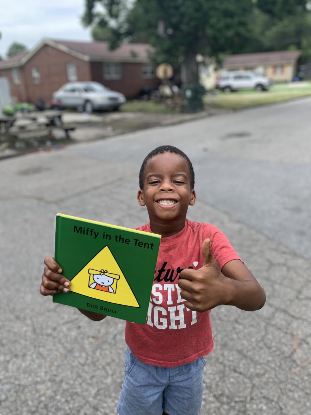 A kid smiles with an animal-friendly book from PETA fieldworkers