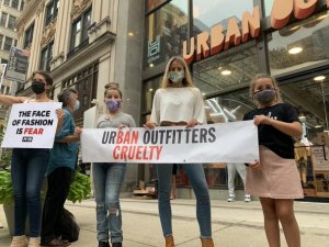 PETA affiliates stand outside Urban Outfitters in Philadelphia holding a sign saying "UrBAN Outfitters Cruelty"