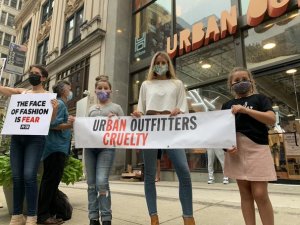 PETA affiliates stand outside Urban Outfitters in Philadelphia holding a sign saying "UrBAN Outfitters Cruelty"