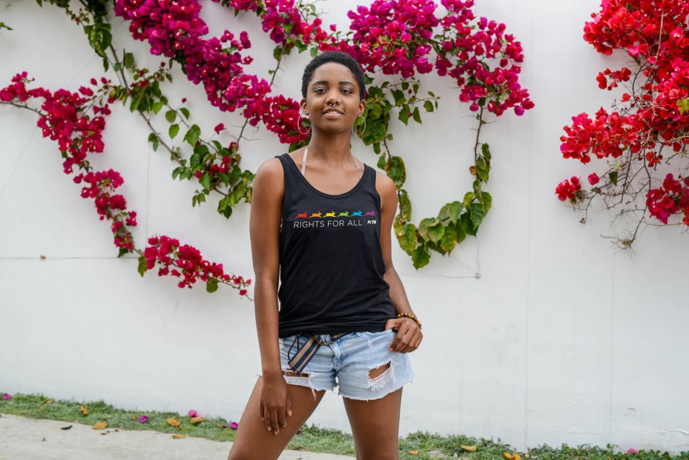 Person wearing PETA Pride tank in front of flower wall