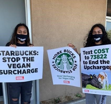 2 students protest the Starbucks vegan milk charge with signs