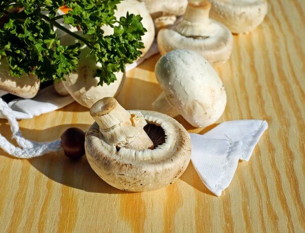 White button mushrooms on a wood board