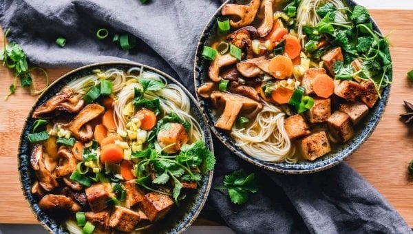 Two bowls of vegan food, noodles and vegetables