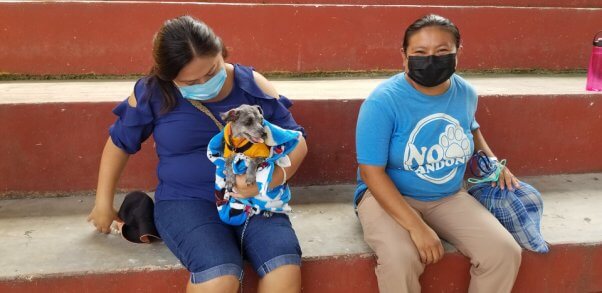 2 guardians wait in line with their animal companion, a dog and cat, for the PETA Chichimila clinic