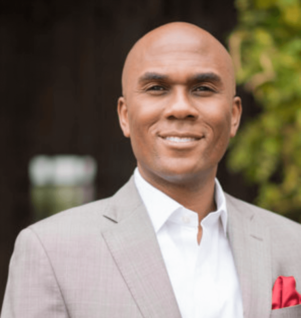 Dr. Batiste poses for a portrait in a light grey suit