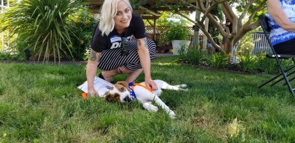 woman petting dog lying on grass at PETA adoption event
