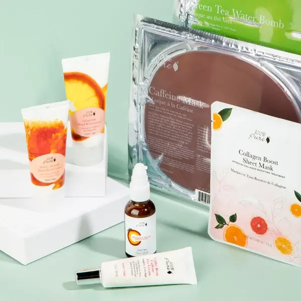 The caffeine mask, brown, is shown in a clear case and surrounded by other products in the Animal Rescue Sets from 100% Pure, like the Collagen Boost Sheet Mask, on a green backgrund