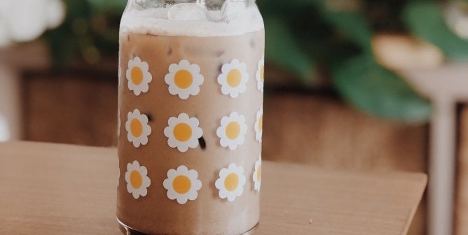 an iced cinnamon brown sugar oat milk latte in a cup with flowers on it