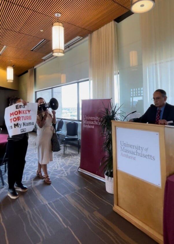 A protester holds a megaphone and another holds a sign at a UMass new faculty orientation