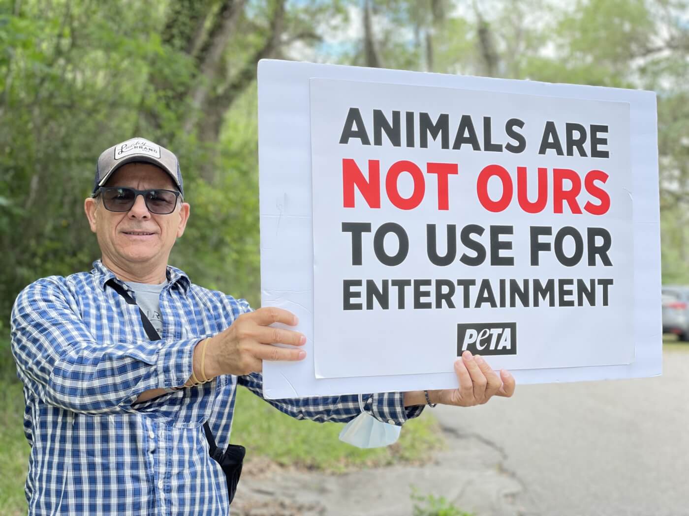 person holding sign that says animals are not ours to use for entertainment