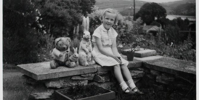 Young Ingrid Newkirk sitting on a brick ledge outside