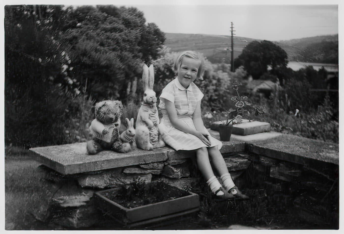 Young Ingrid Newkirk sitting on a brick ledge outside
