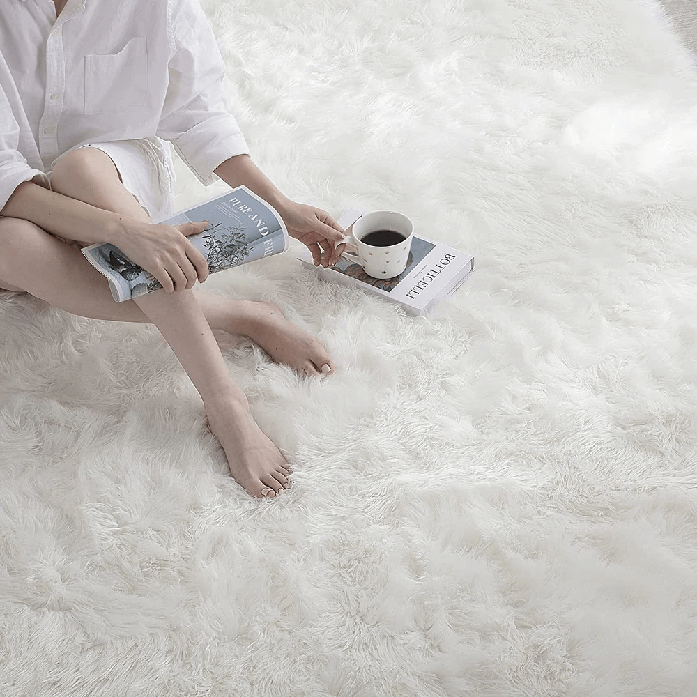 woman sitting on a white faux sheepskin rug with a cup of coffee